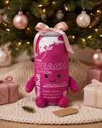 The Peach energy can plushie with a pink satin bow under a Christmas tree, the gift for your redbullholic